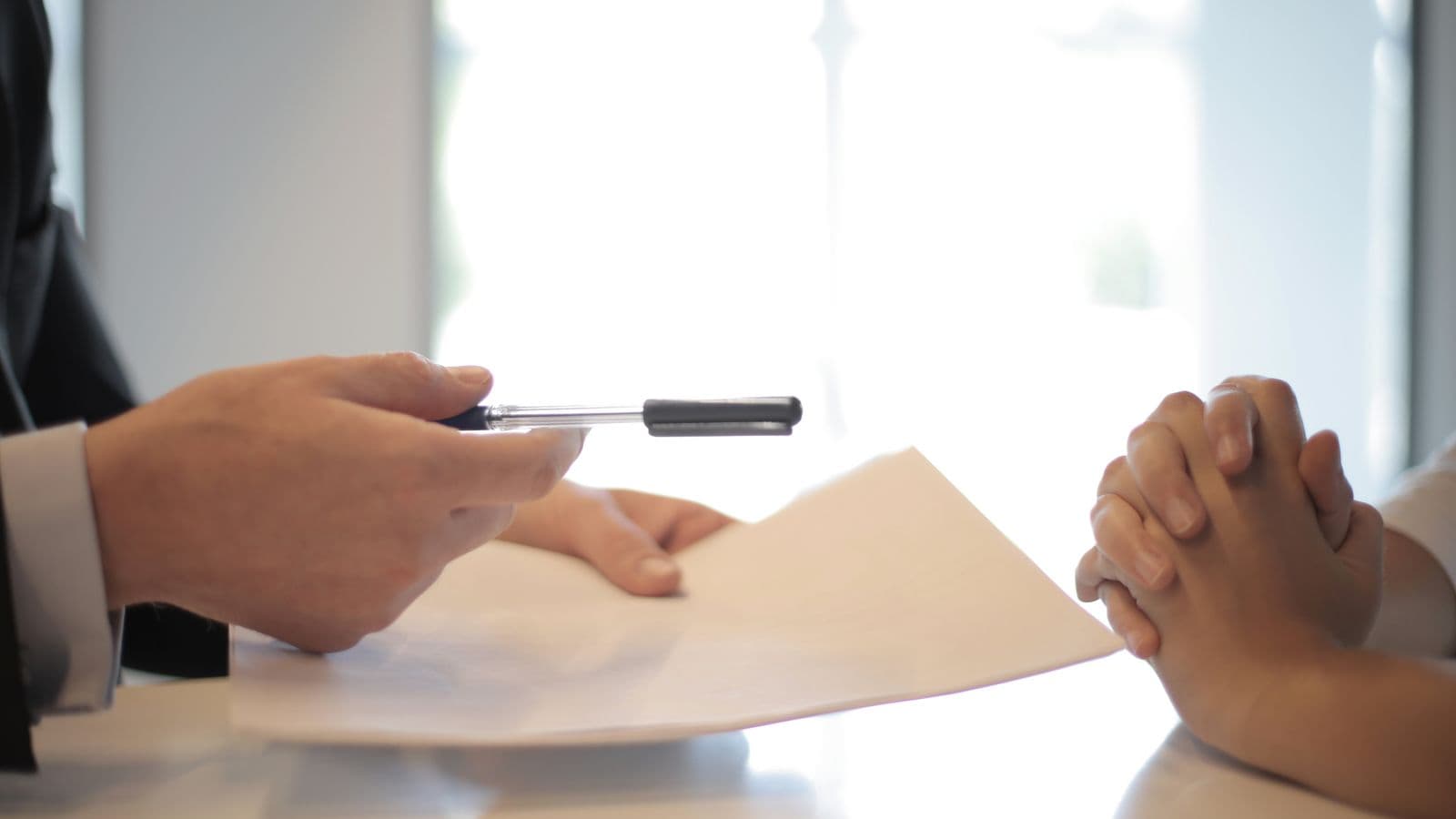 Deux personnes échangeant un document d'assurance à signer dans un bureau