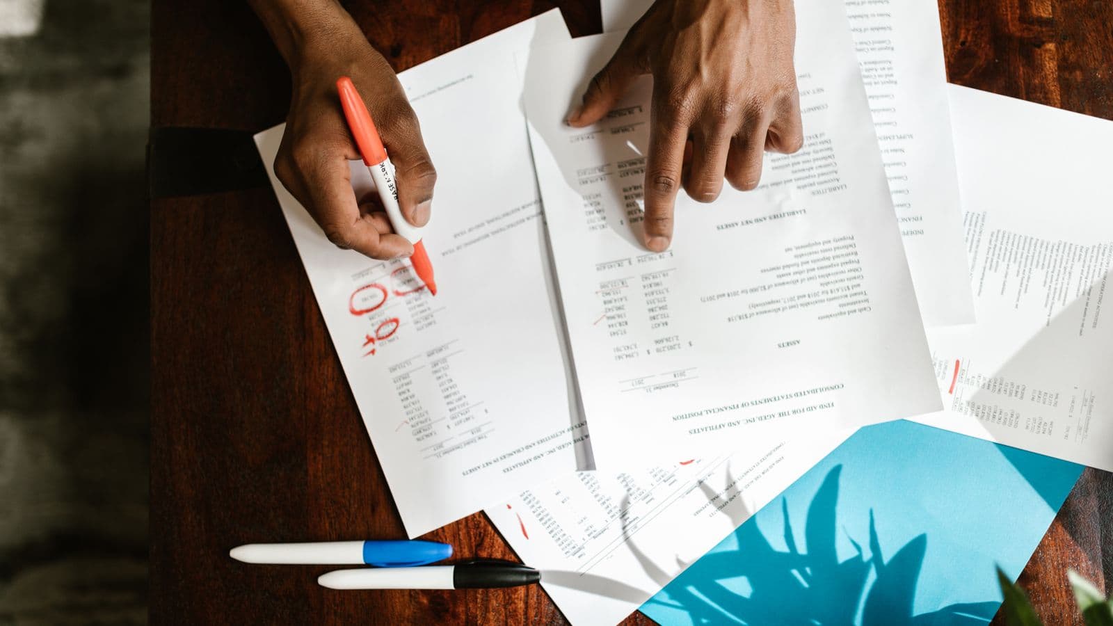 Mains feuilletant des documents financiers sur un bureau, illustrant l'analyse des avantages de toute nature