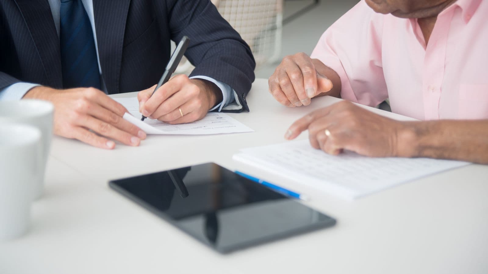 Deux professionnels discutant et signant des documents, illustration du choix d'une caisse d'assurances sociales en Belgique