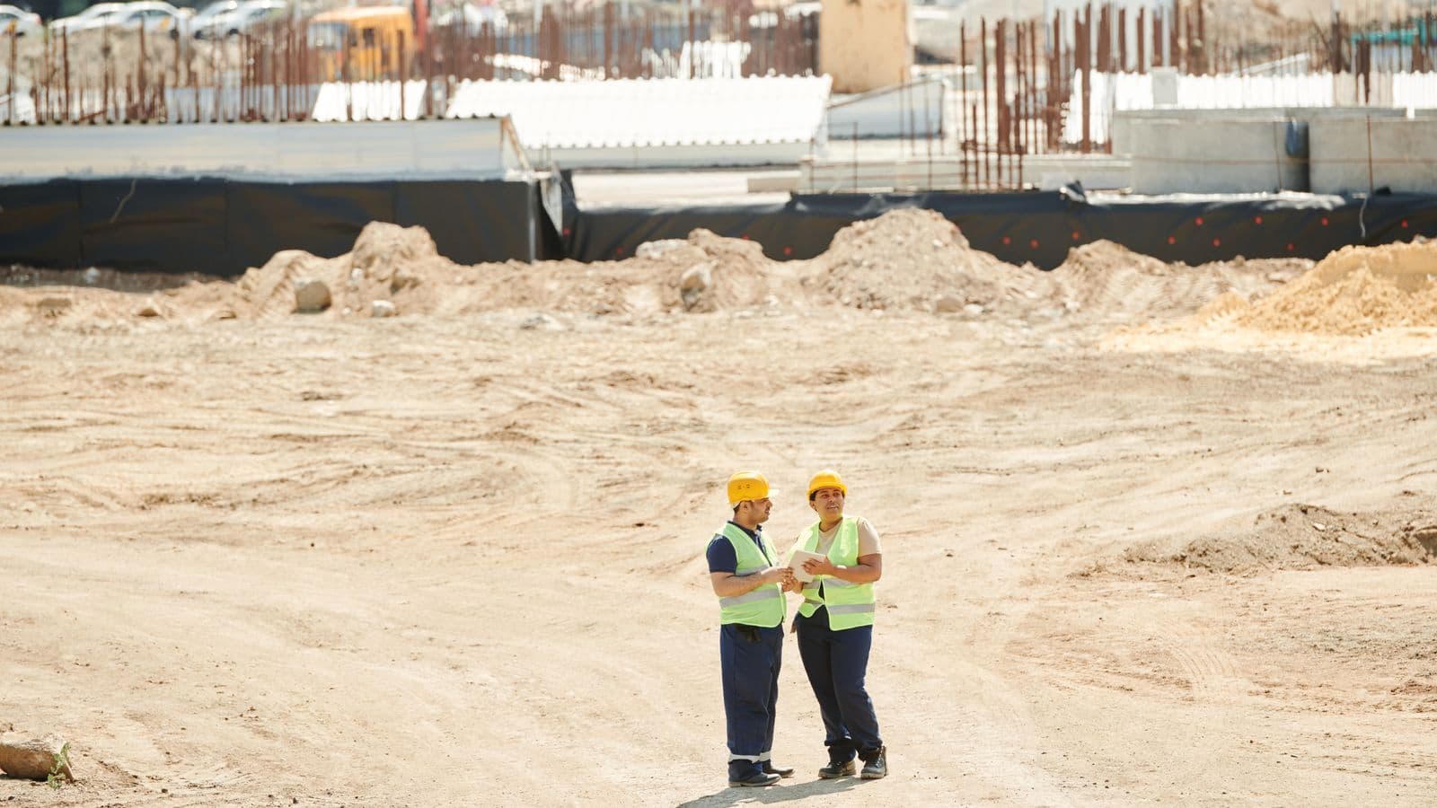 Deux ouvriers en équipement de sécurité discutant des plans sur un chantier de construction