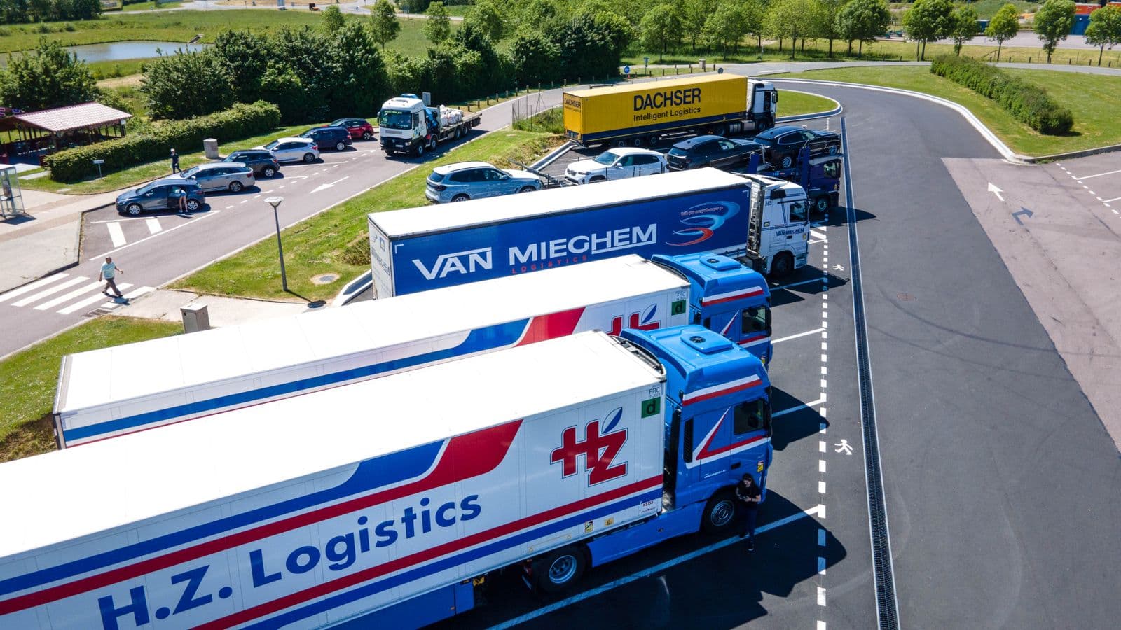 Flotte de camions de transport et de logistique stationnés sur une aire d'autoroute, vue aérienne