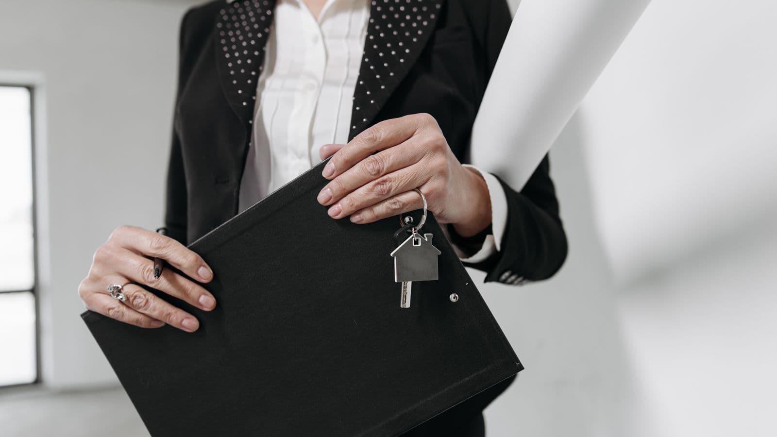 Agent immobilier remettant les clés d'un logement à un couple devant un immeuble