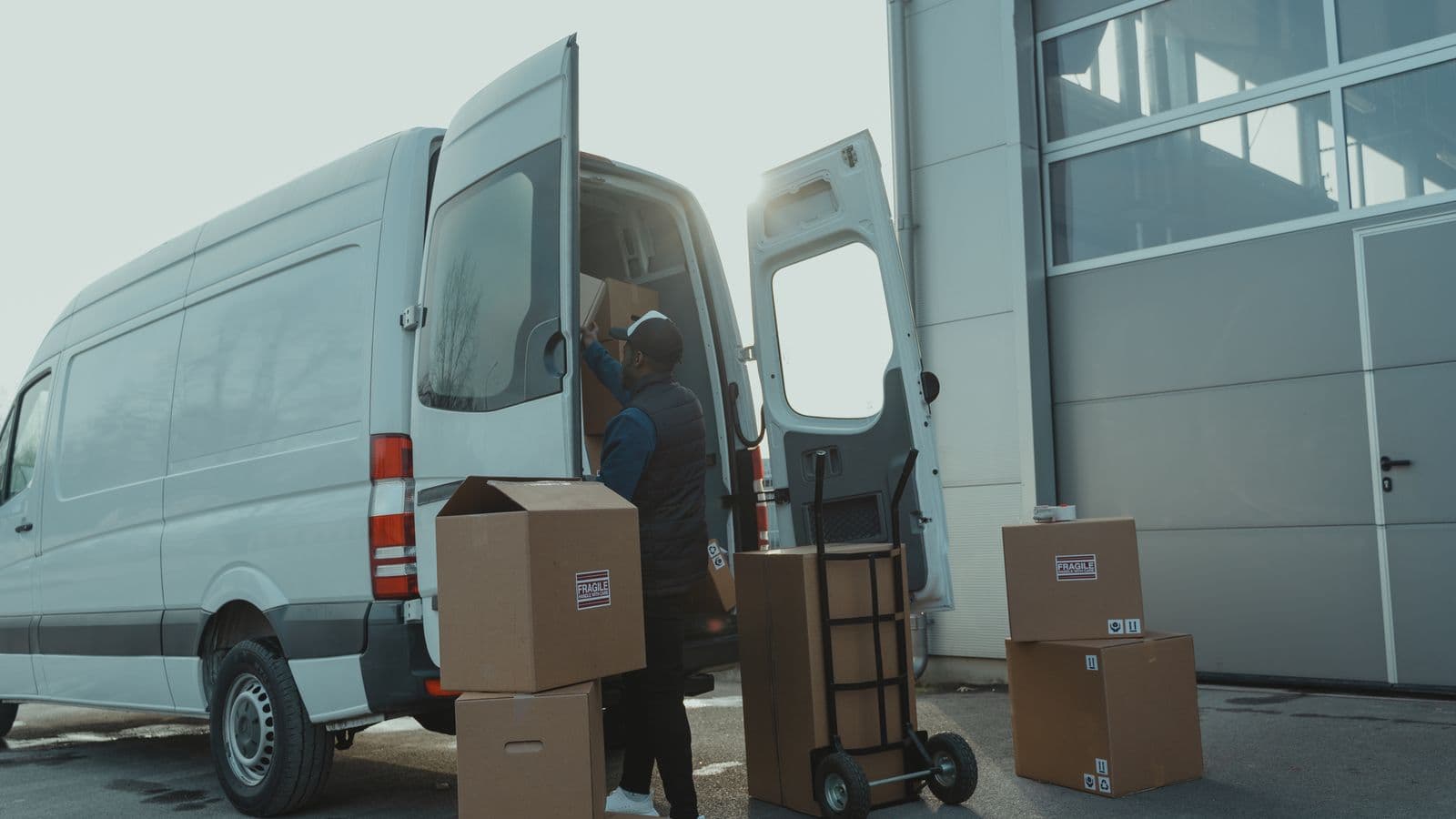 Coursier chargeant des colis dans une camionnette de livraison, illustration du métier de chauffeur indépendant en Belgique