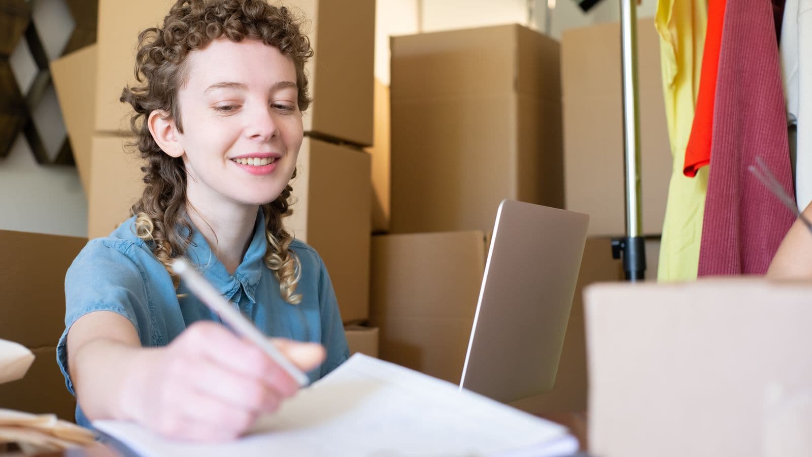 Jeune entrepreneure indépendante gérant sa petite activité sur un ordinateur portable entouré de colis