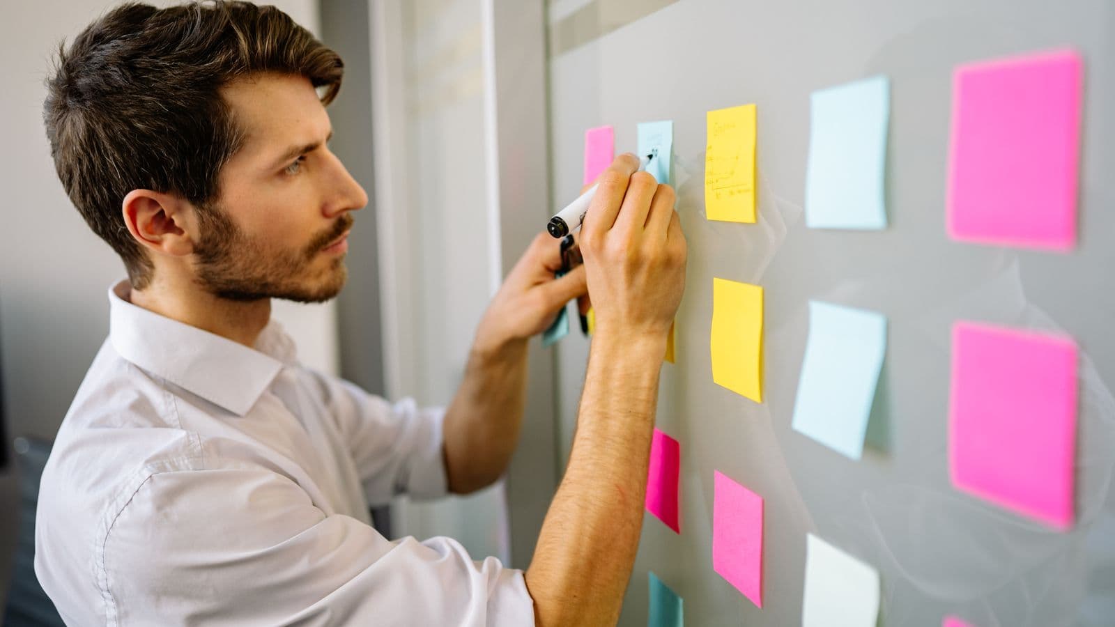Entrepreneure belge réfléchissant à des idées de business rentables devant un tableau de notes et un ordinateur portable