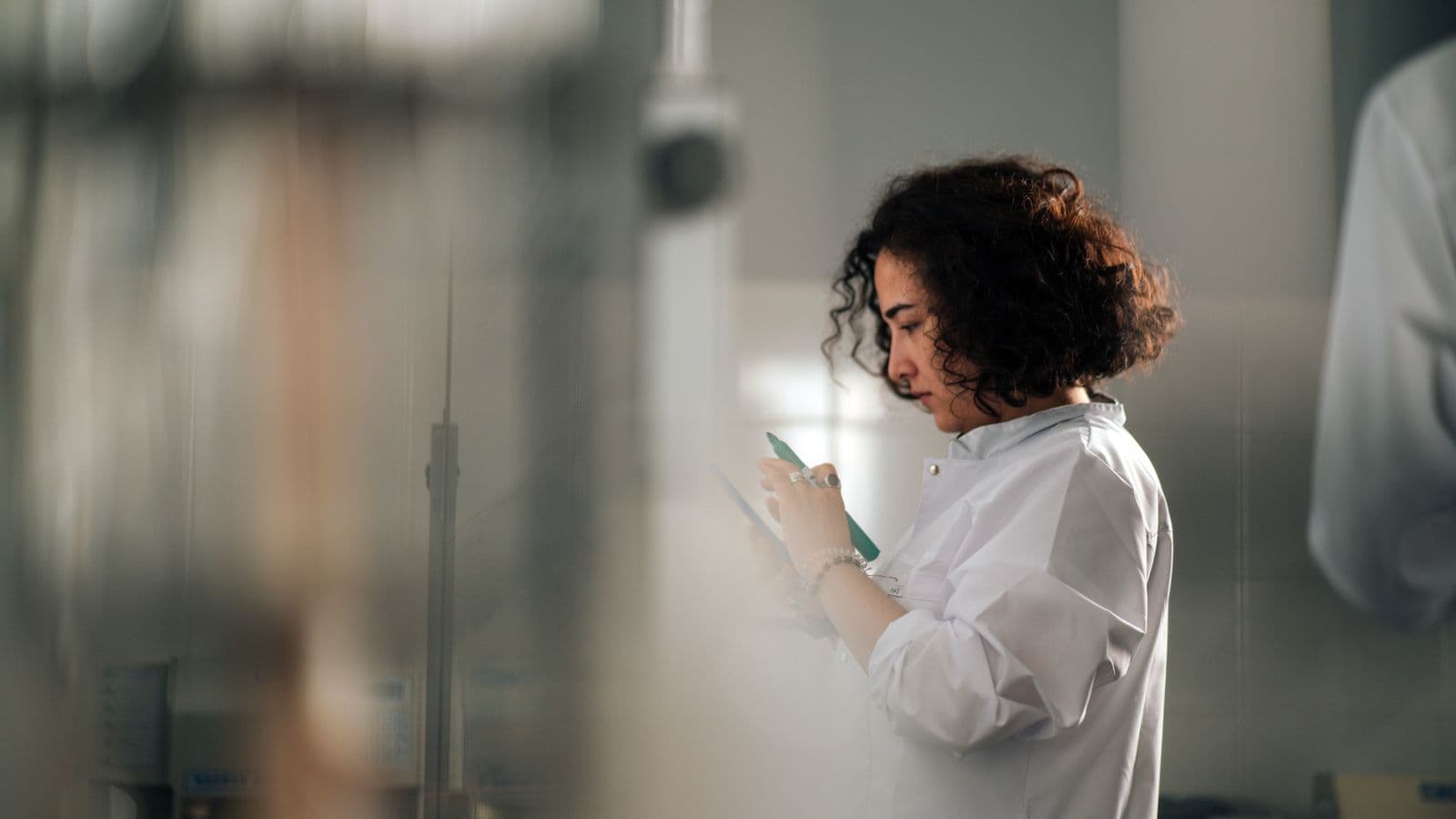 Une chercheuse en blouse de laboratoire prend des notes au cours d'un projet de recherche et développement