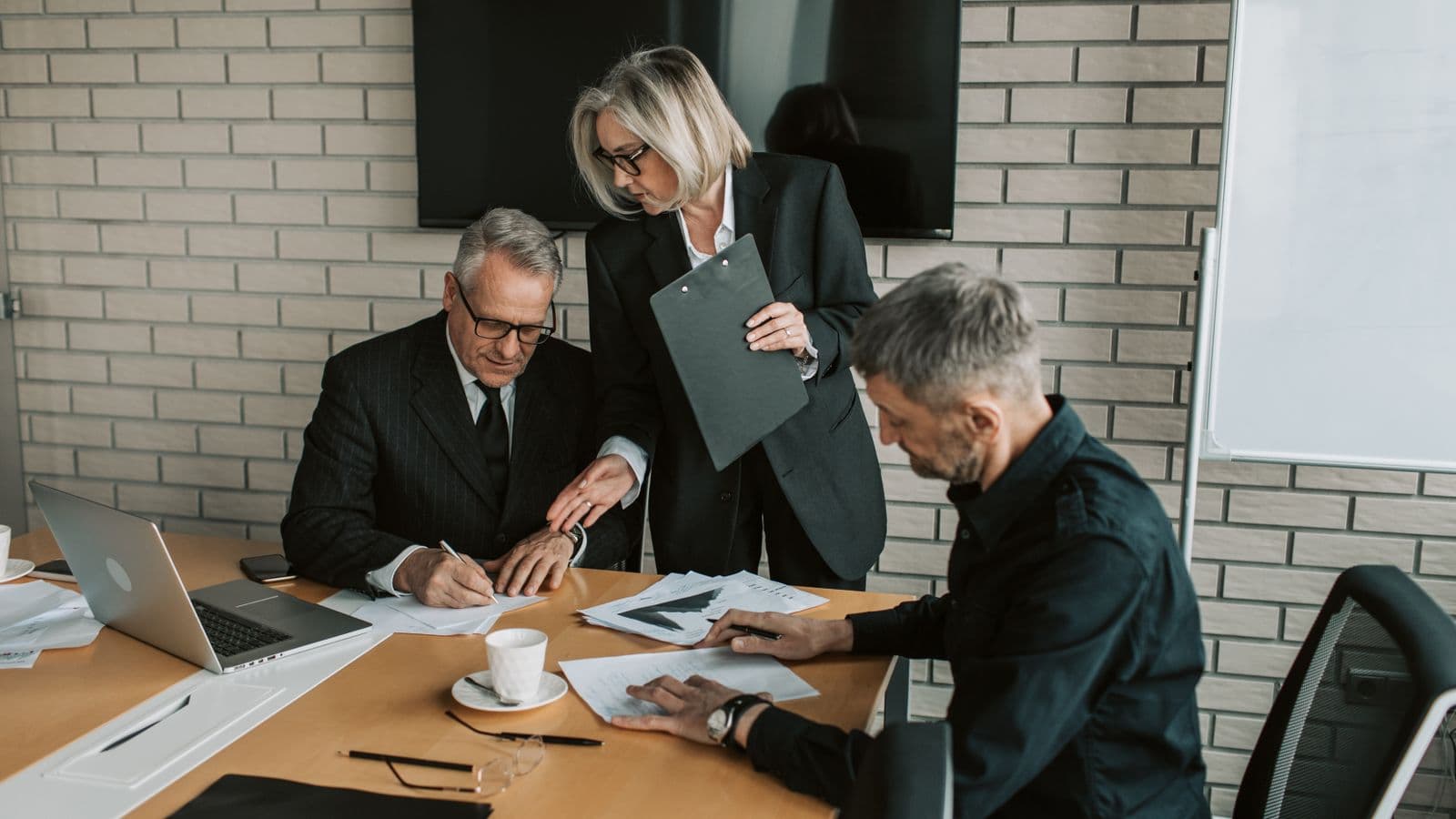 Trois professionnels échangent et signent des documents lors d'une réunion en entreprise