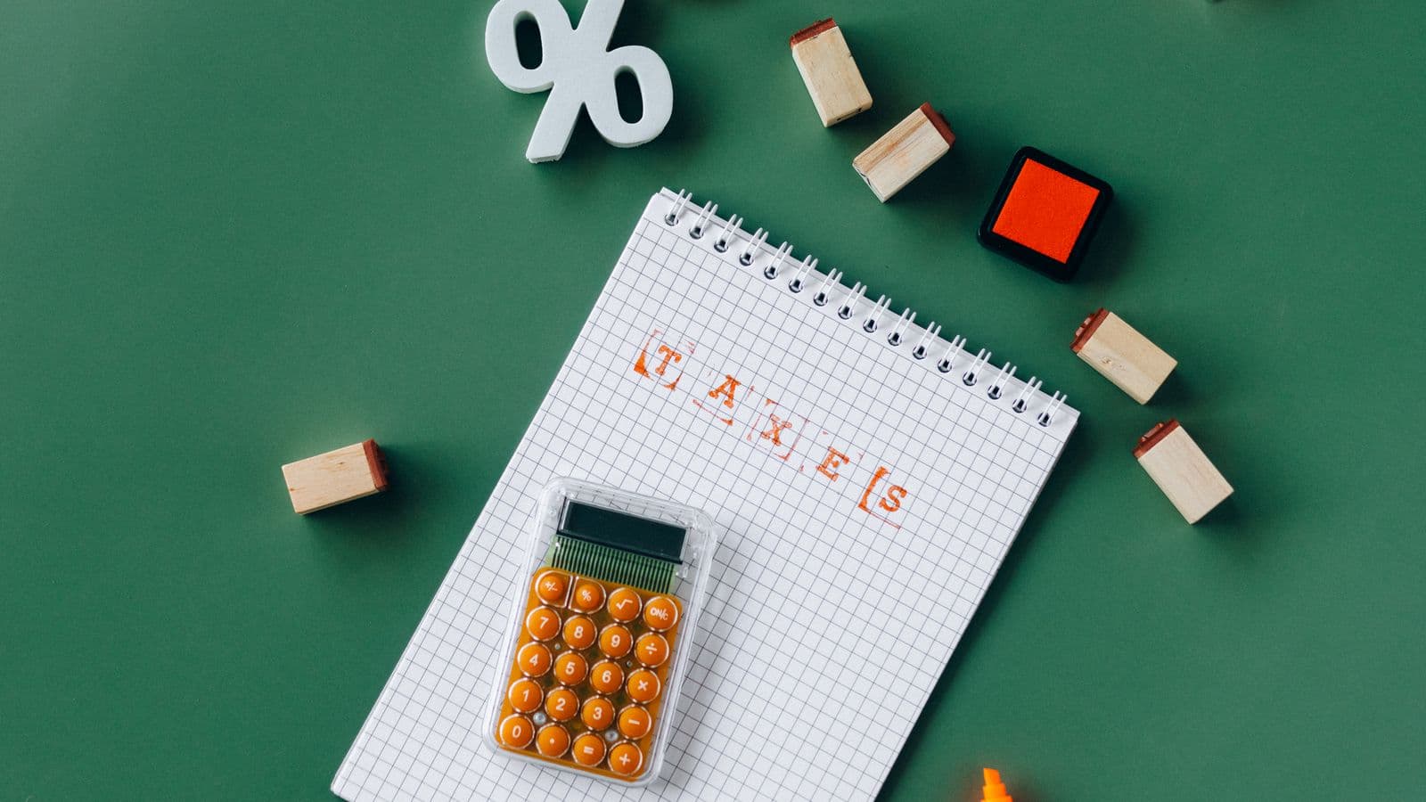Tampons et calculatrice autour d'un bloc-notes marqué du mot taxes, évoquant une dette fiscale