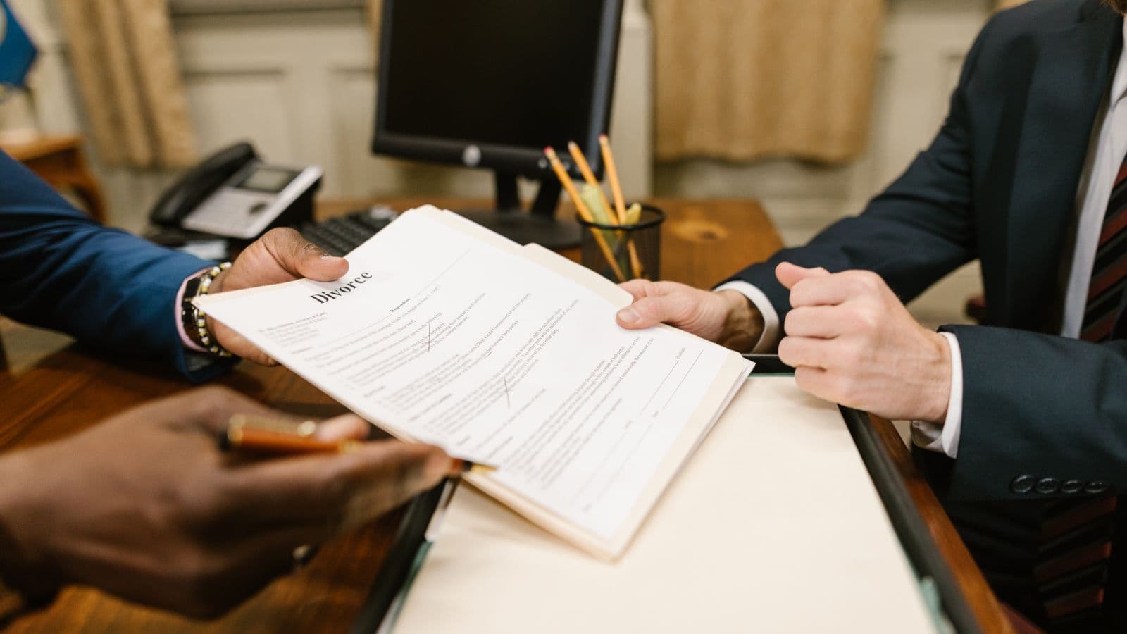 Mains échangeant des documents juridiques lors d'une réunion, illustration du service juridique en entreprise
