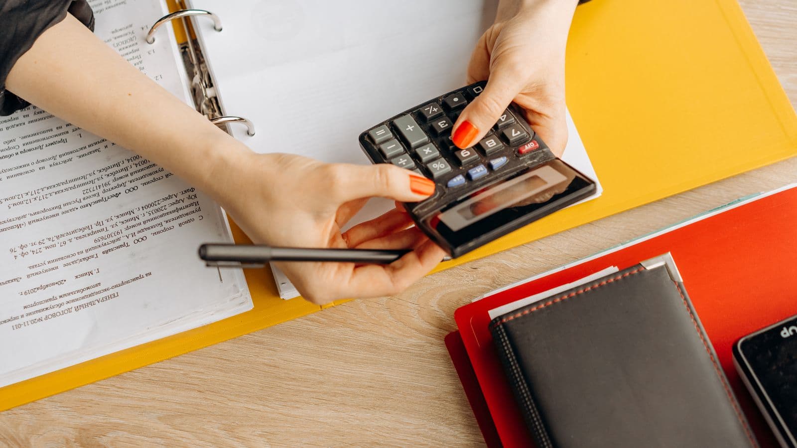 Comptable utilisant une calculatrice avec des documents financiers sur un bureau de travail