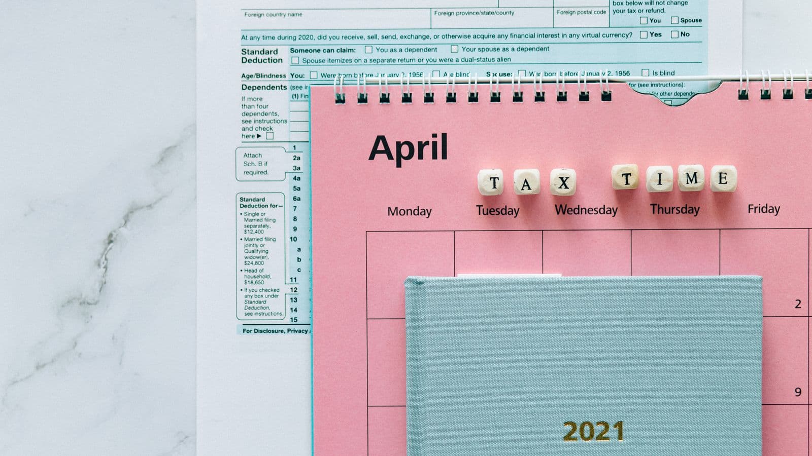 Calendrier d'avril avec formulaires fiscaux sur un bureau, illustrant les échéances des versements anticipés en Belgique