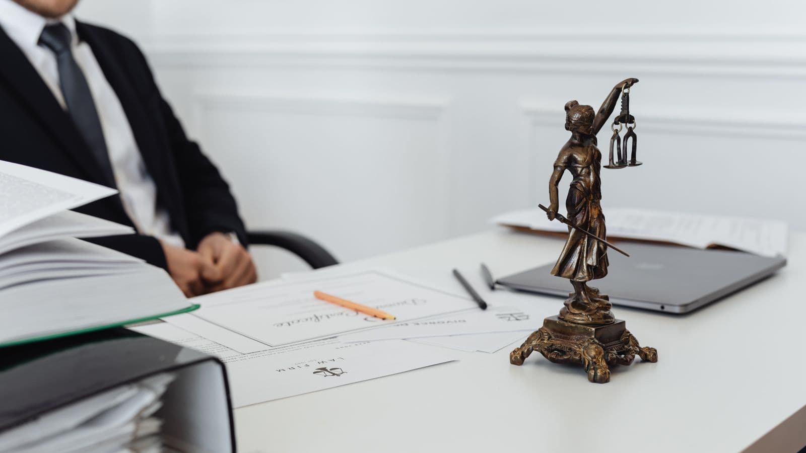 Espace de travail juridique avec statuette de la Justice, documents officiels et ordinateur portable sur un bureau