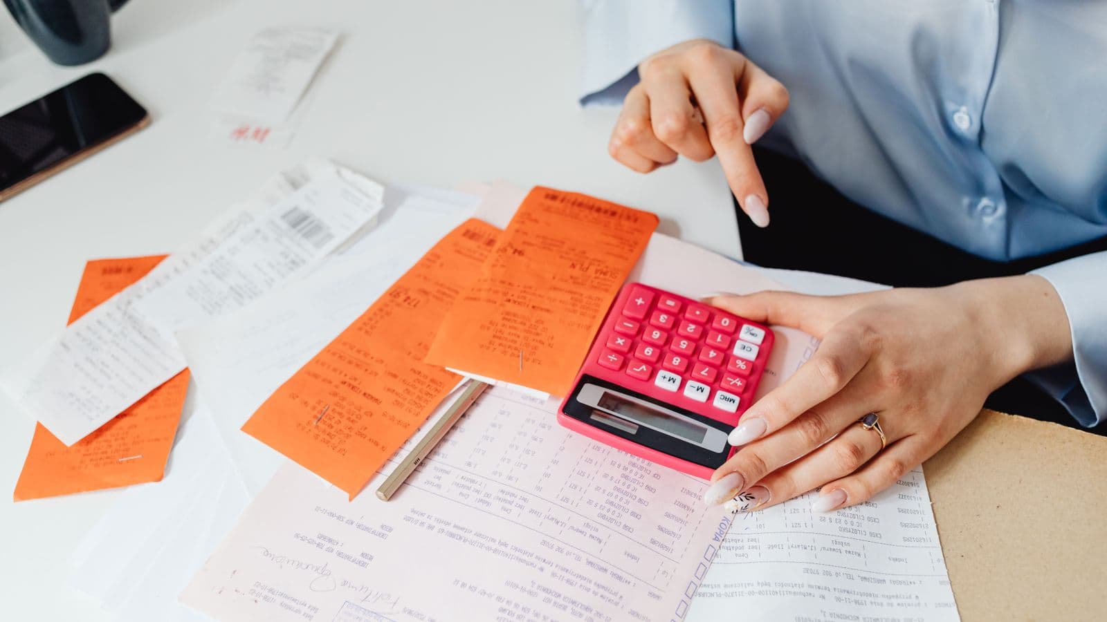 Femme d'affaires qui calcule des frais avec une calculatrice et des reçus sur un bureau