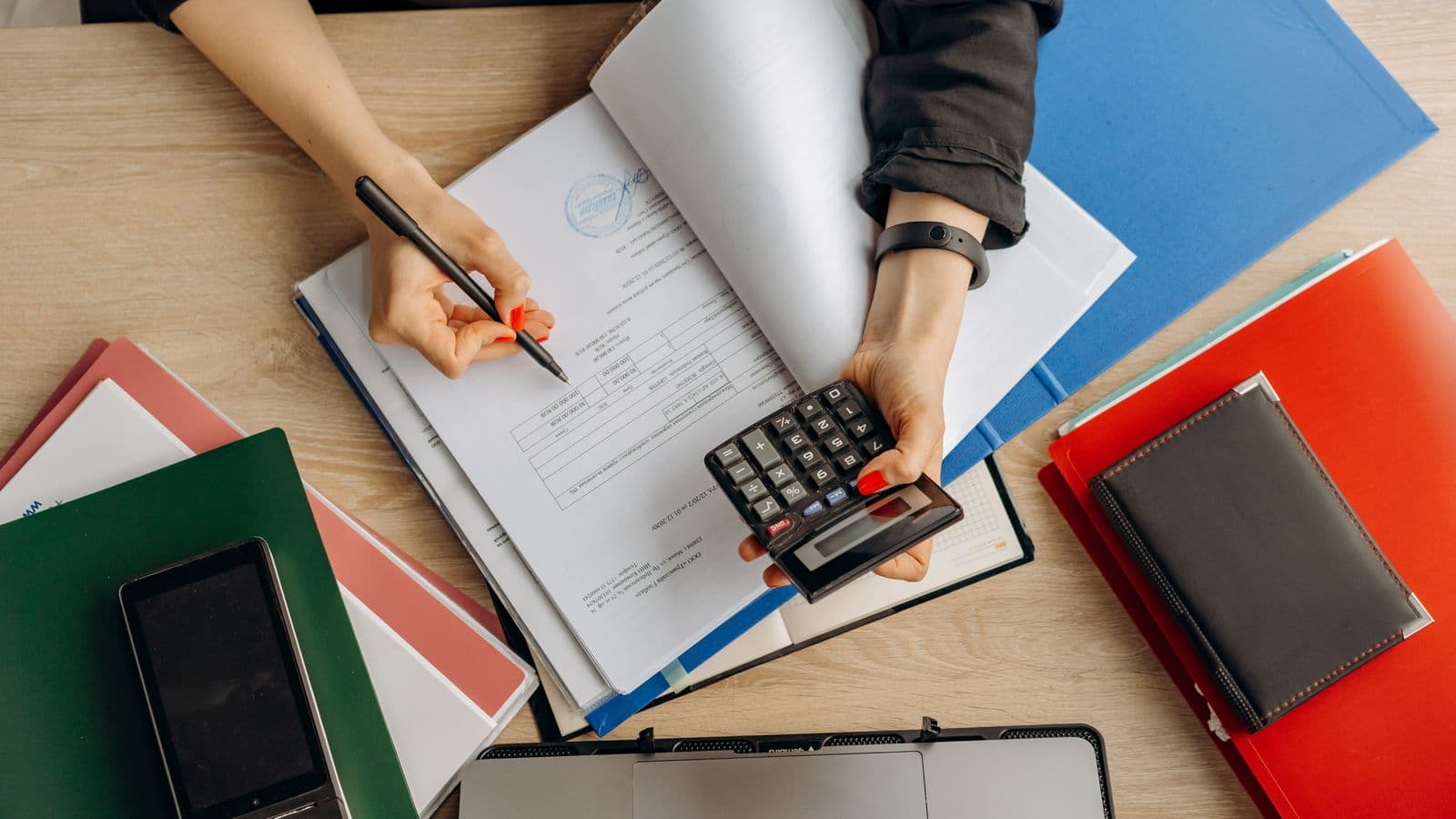 Comptable analysant des documents financiers avec une calculatrice sur un bureau professionnel