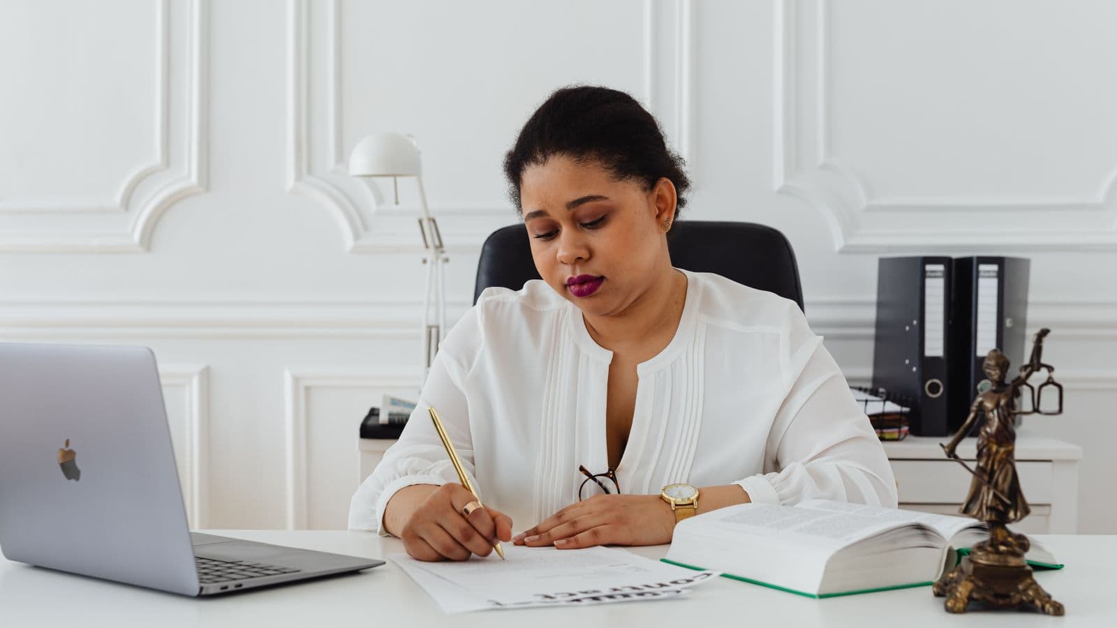Signature de l'acte constitutif d'une société sur un bureau, statuette de la justice à côté