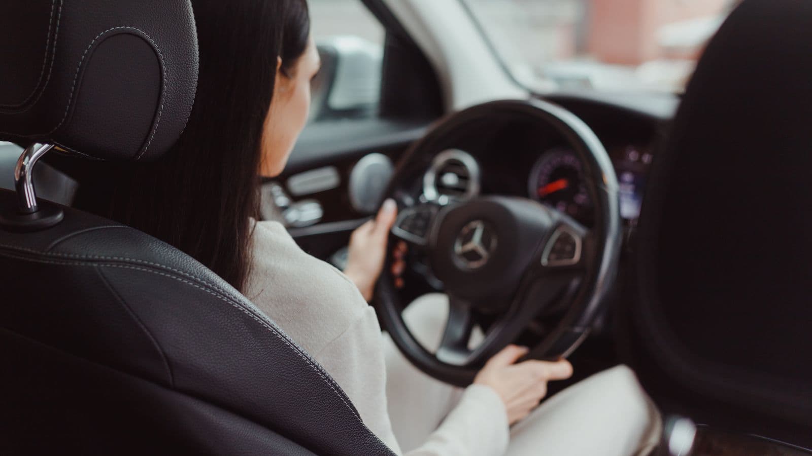 Conducteur au volant de sa voiture en ville, vue depuis l'intérieur de l'habitacle