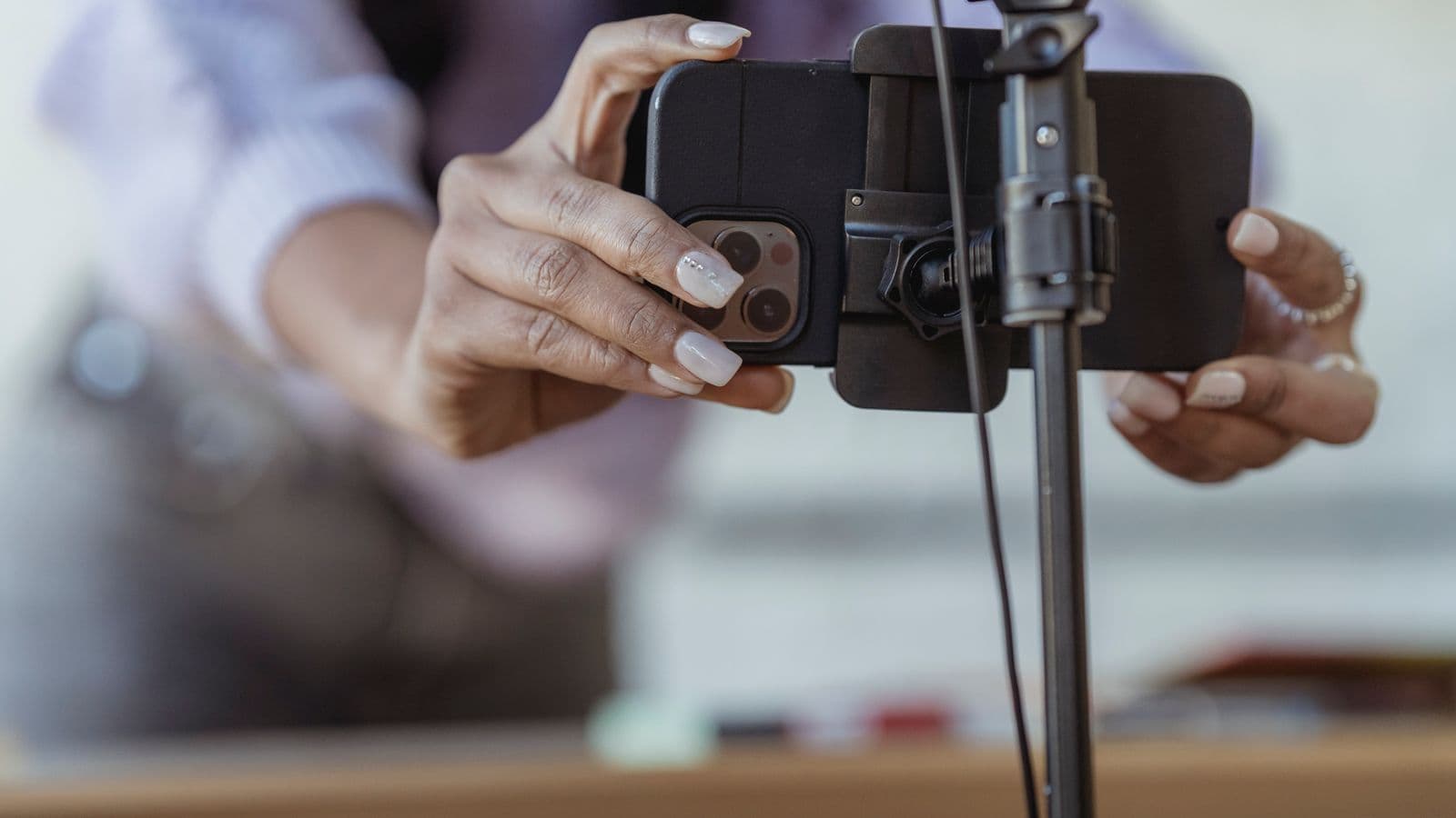 Personne installant un smartphone sur un trépied pour filmer une vidéo, illustration de la réussite sur TikTok en Belgique