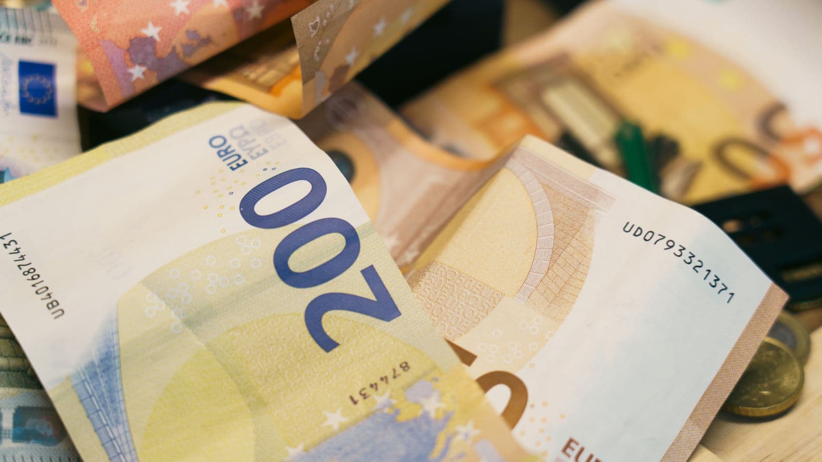 Billets et pièces en euros empilés sur un bureau, illustrant le montant des amendes administratives du registre UBO