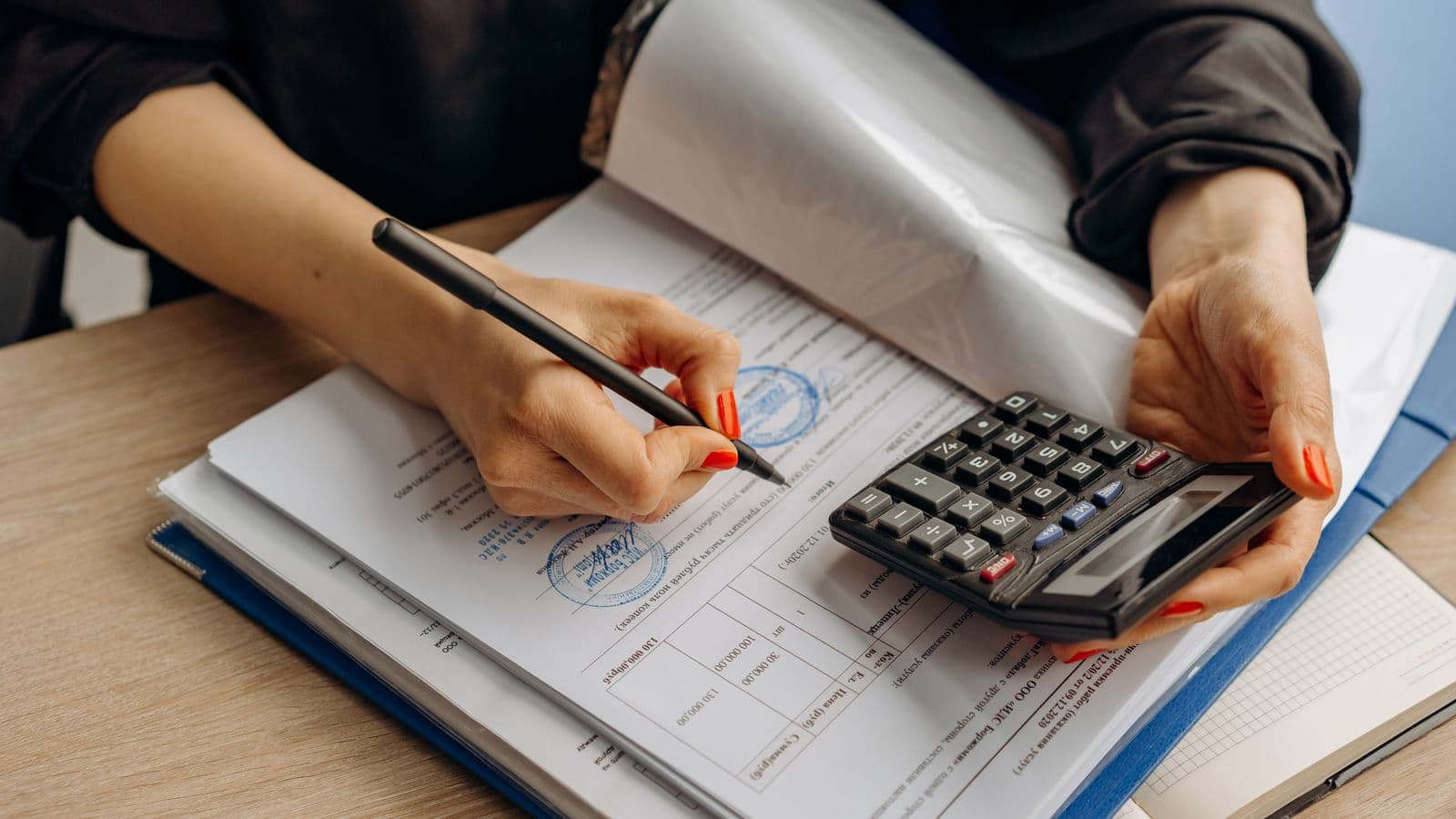 Comptable utilisant une calculatrice et signant des documents fiscaux pour l'impôt des sociétés belge