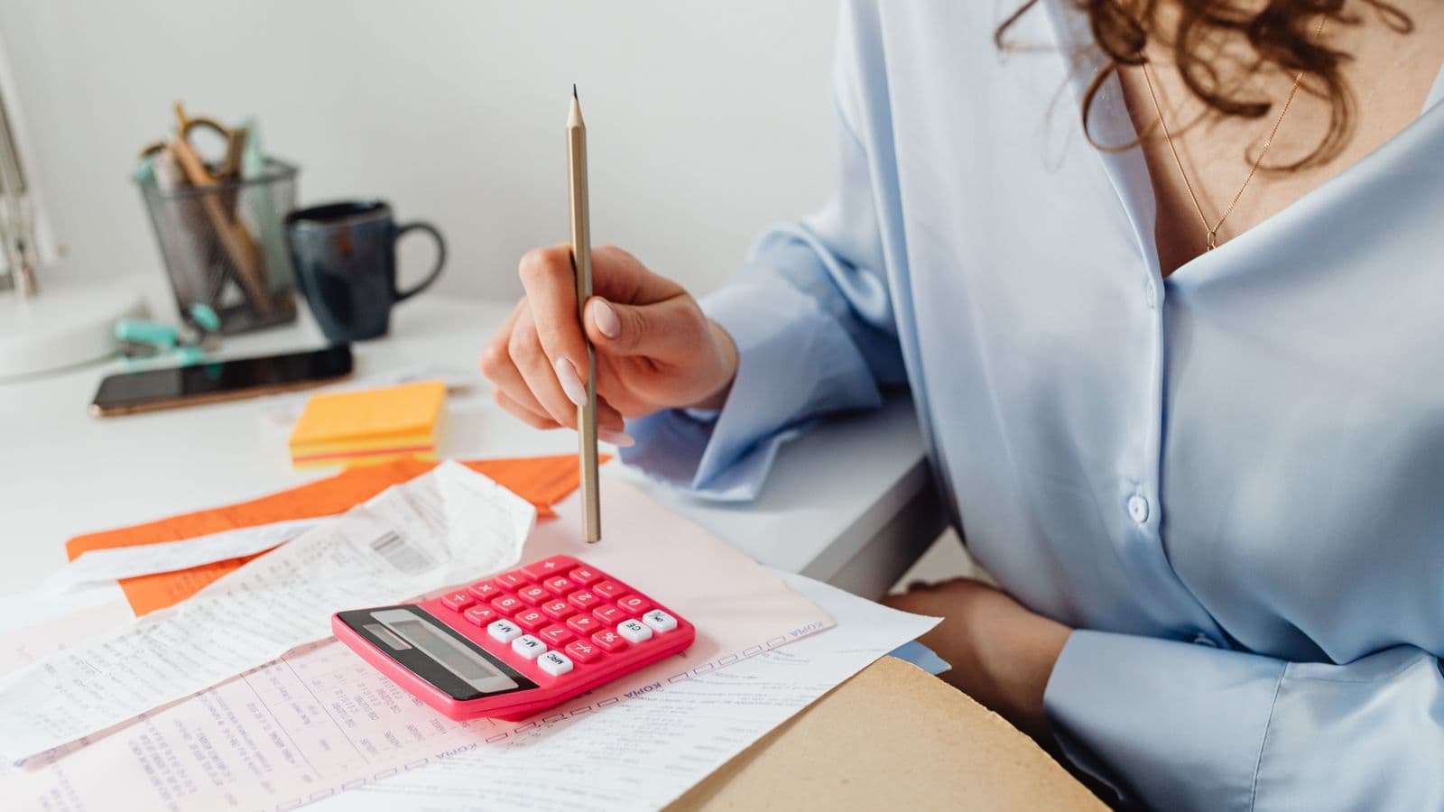 Comptable calculant des montants à l'aide d'une calculatrice et de documents financiers sur un bureau